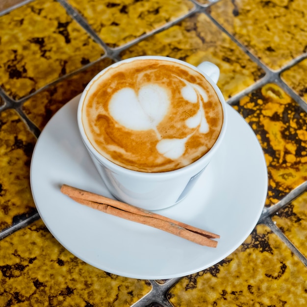 Una tazza di caffè latte e bastoncino di cannella.