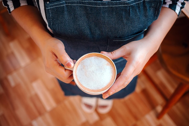 Una tazza di caffè menu cappuccino pronto a servire in mano donna barista nella caffetteria