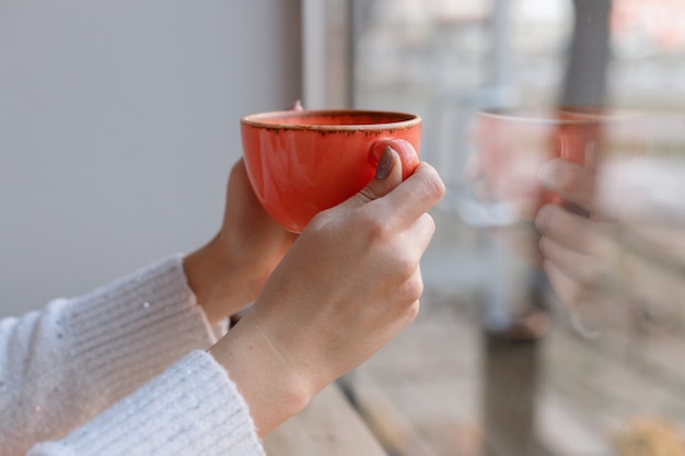 Una tazza di caffè nelle mani di una donna in primo piano