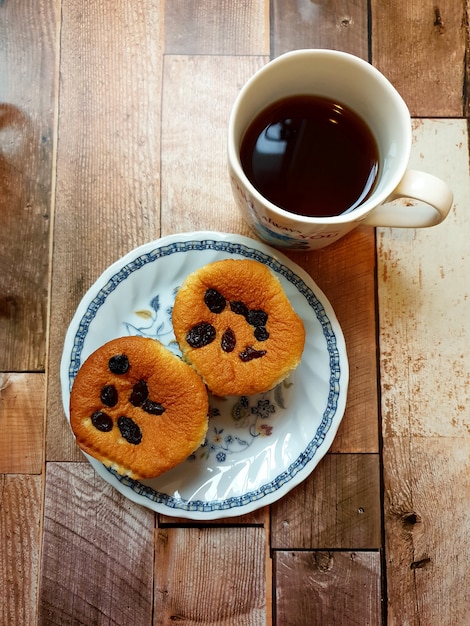 Una tazza di caffè nero caldo con muffin all'uvetta su uno sfondo di legno