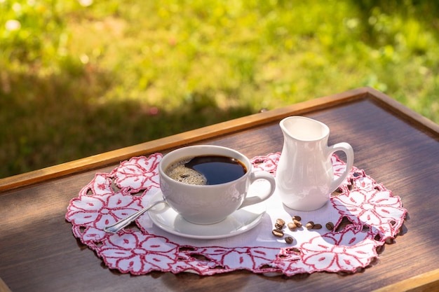 Una tazza di caffè nero e latte su un tavolo su sfondo naturale in giardino