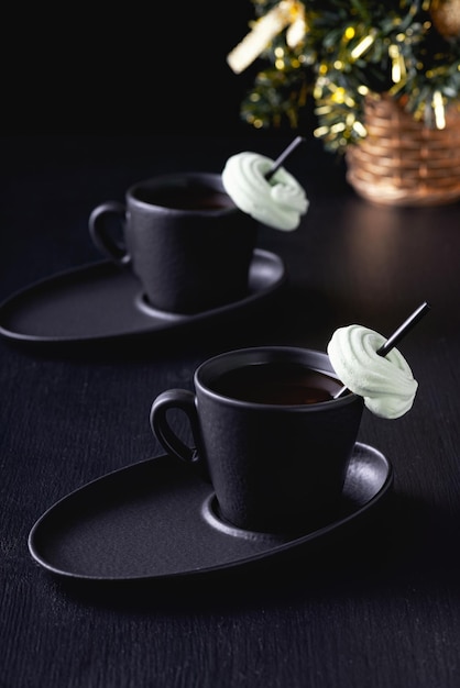 Una tazza di caffè o tè caldo e un albero di Natale su un tavolo nero