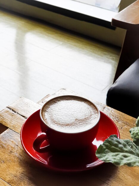 Una tazza di caffè rossa su un piattino rosso