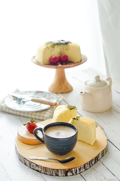 Una tazza di caffè servita con la torta su un vassoio di legno.