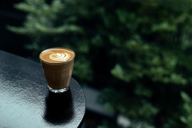 Una tazza di caffè si trova su un tavolo con uno sfondo verde.