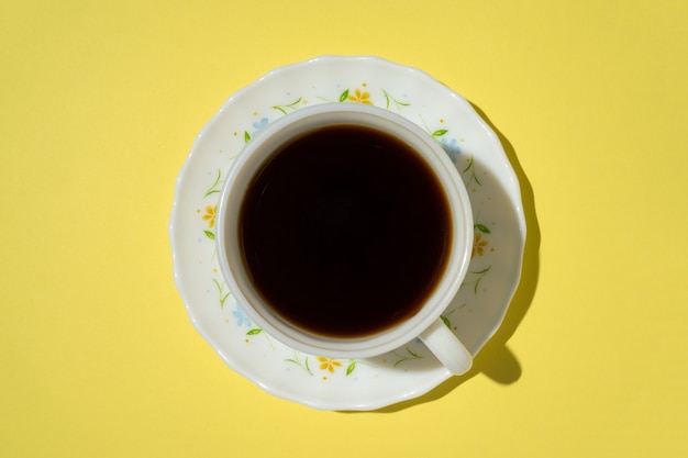 Una tazza di caffè su sfondo giallo.