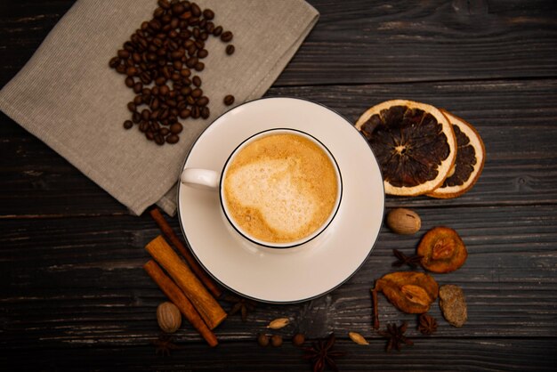 Una tazza di caffè su un fondo di legno con le spezie