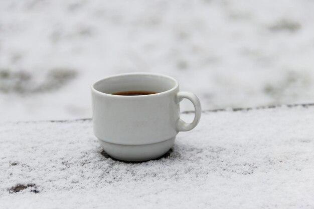 Una tazza di caffè su un tavolo coperto di neve in inverno