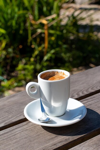 Una tazza di caffè su un tavolo sullo sfondo della natura in giardino