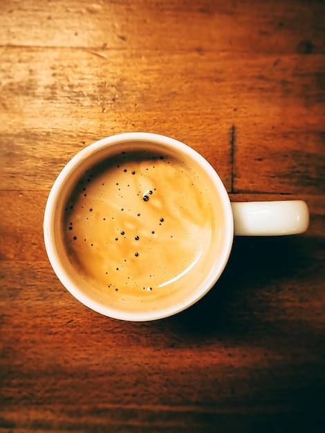 Una tazza di caffè sul tavolo di legno.