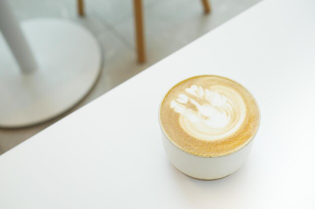 Una tazza di caffè tardivo con un disegno a forma di fiore in cima al bar