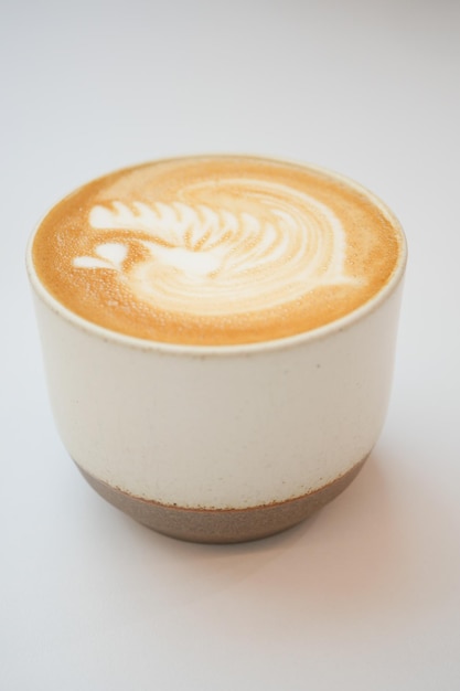 Una tazza di caffè tardivo con un disegno a forma di fiore in cima al bar