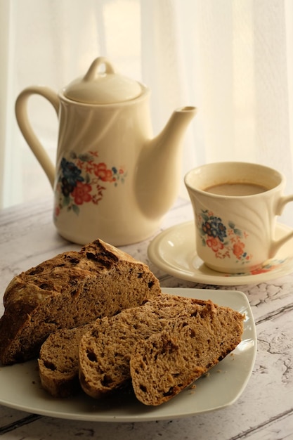 una tazza di caffè, una teiera e fette di pane nero a lievitazione naturale. su un tavolo di legno. colazione. senza glutine