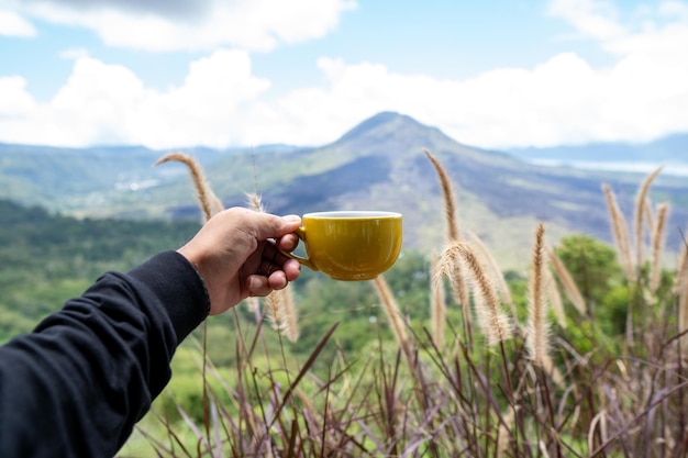 Una tazza di caffè viene sollevata davanti alla vista del Monte Batur