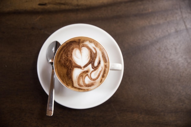 Una tazza di cappuccino caldo è in piedi sul tavolo di legno