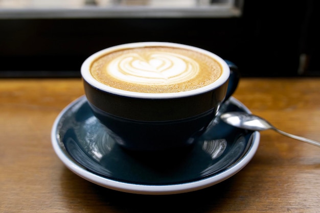 una tazza di cappuccino sul tavolo di legno vicino alla finestra in un bel caffè