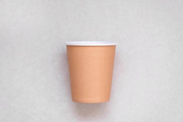 Una tazza di carta marrone su uno sfondo bianco con sopra la parola caffè.