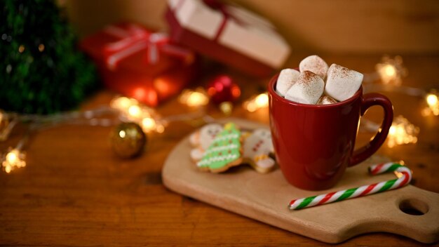 Una tazza di cioccolata calda con marshmallow sulla tavola di legno con decorazioni natalizie