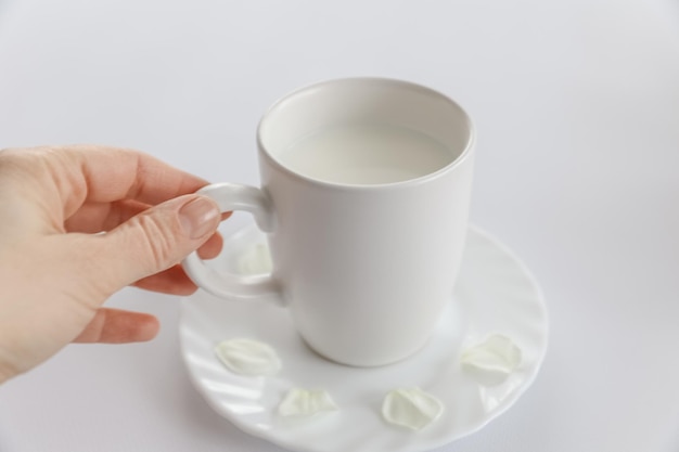 Una tazza di latte in mano su uno sfondo bianco