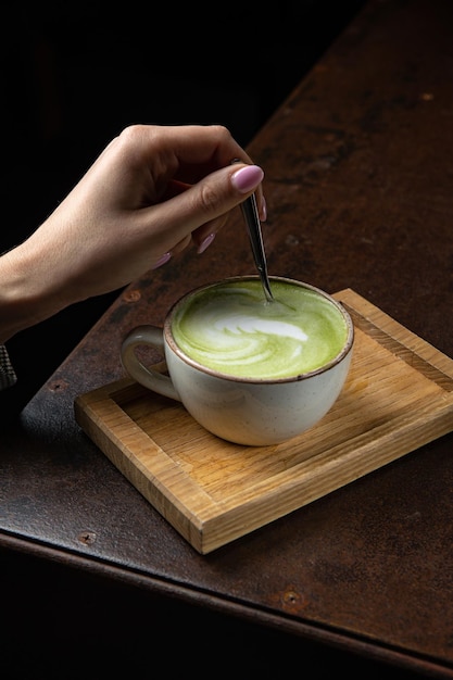 Una tazza di latte matcha con un cucchiaio su un vassoio di legno