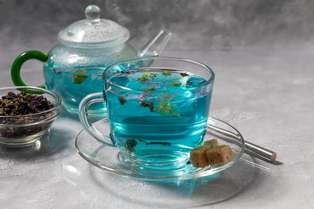 Una tazza di tè blu caldo con fiori di pisello. Piselli Per bere sano, disintossicare il corpo. Tavolo grigio