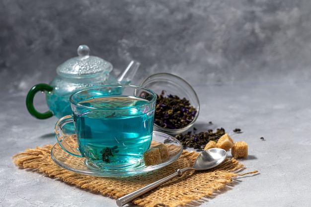 Una tazza di tè blu caldo con fiori di pisello. Piselli Per bere sano, disintossicare il corpo. Tavolo grigio