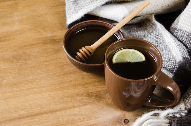 Una tazza di tè caldo con limone, miele e plaid.