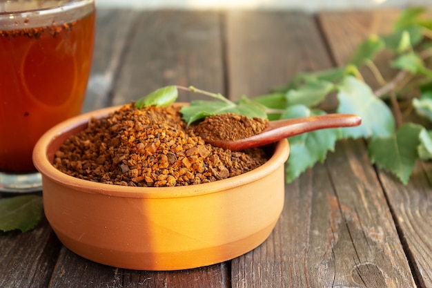 Una tazza di tè chaga su un tavolo scuro, fette di chaga e un ramoscello di betulla, messa a fuoco selettiva