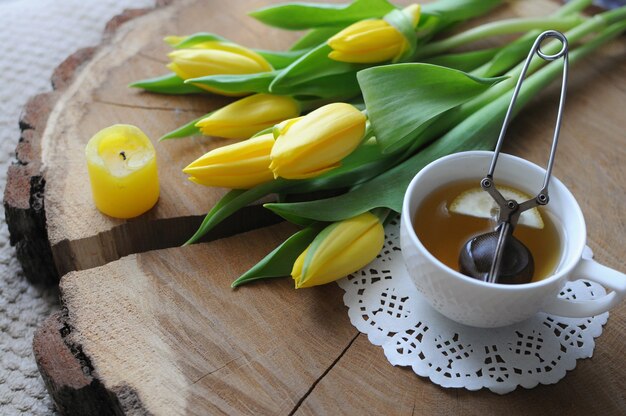 Una tazza di tè con la teiera con i tulipani gialli sulla tavola di legno. Colazione a letto