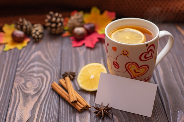 Una tazza di tè con limone e bastoncini di cannella su un tavolo di legno caldo umore autunnale snood a maglia
