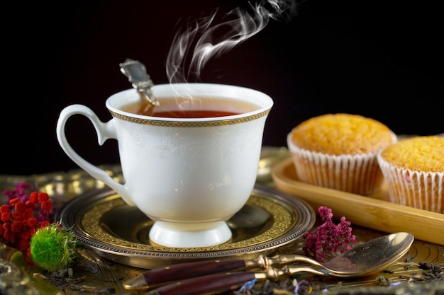 Una tazza di tè con un cucchiaio dentro e un muffin su un piatto.