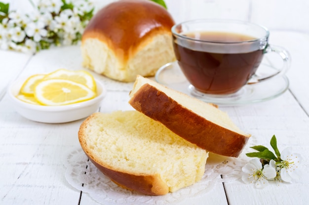 Una tazza di tè con un panino morbido e fette di limone è un buon inizio di giornata. Colazione.