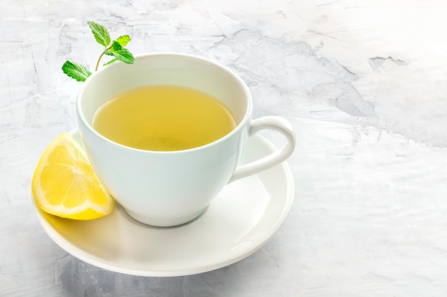 Una tazza di tè con una fetta di limone e foglie di menta con spazio di copia