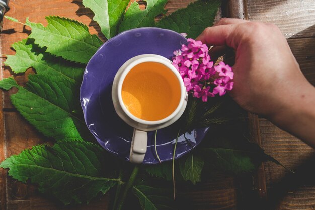 Una tazza di tè con una tazza viola e fiori viola su un tavolo di legno.