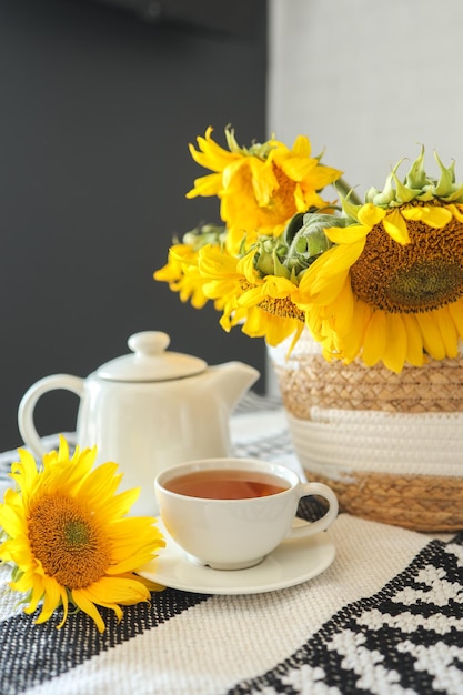Una tazza di tè e una teiera con una candela su un tavolo con l'estetica dell'ora del tè dei girasoli