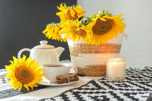 Una tazza di tè e una teiera con una candela su un tavolo con l'estetica dell'ora del tè dei girasoli