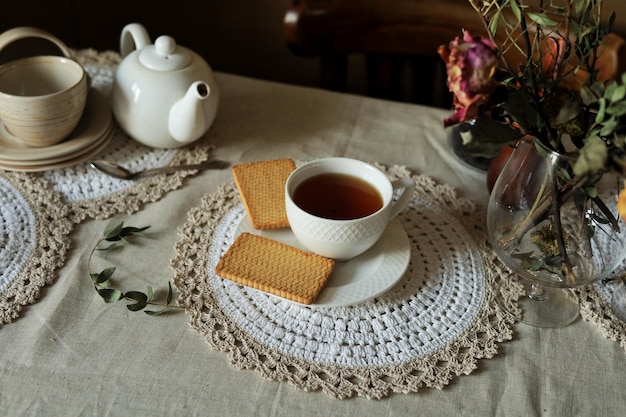 Una tazza di tè nero caldo su un piattino e biscotti sul tavolo Casa ancora in vita