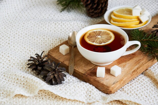 Una tazza di tè nero con zucchero lemonnd su plaid in maglia bianca