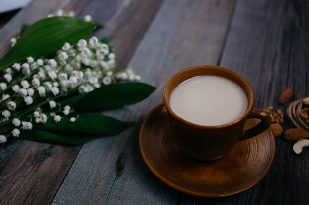 Una tazza di tè, noci, bouquet di gigli su un fondo di legno