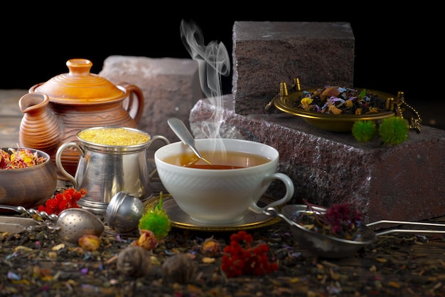 Una tazza di tè si trova su un tavolo con un vassoio di dolci e una teiera con una teiera sullo sfondo.
