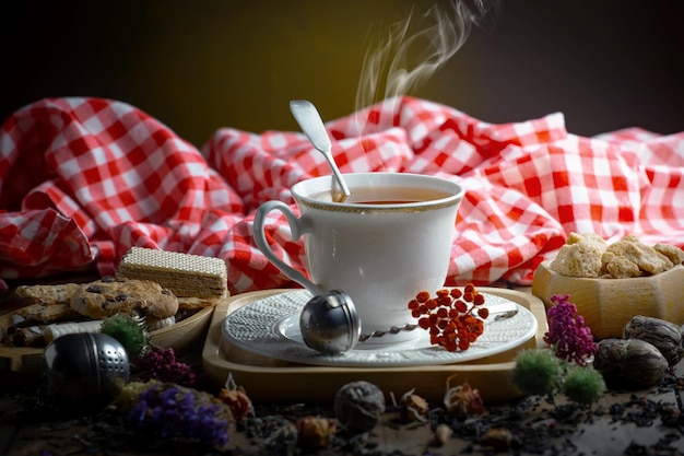 Una tazza di tè si trova su un tavolo con una tovaglia a quadretti rossi e bianchi e una tovaglia a quadretti rossi e bianchi.