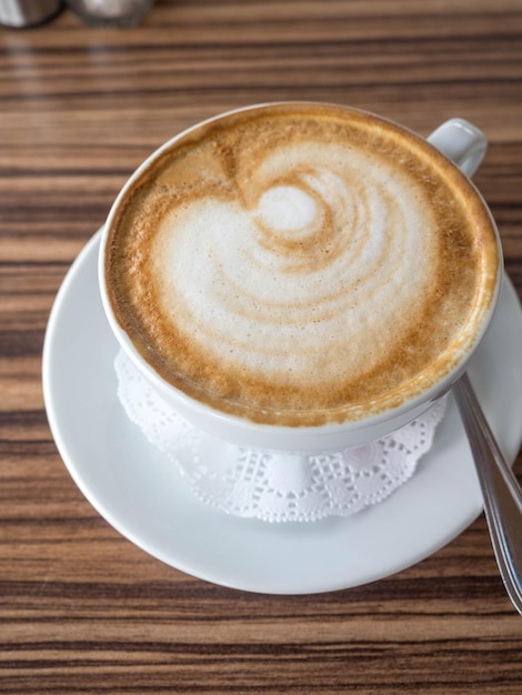 Una tazza in ceramica di caffè latte art sul tavolo di legno