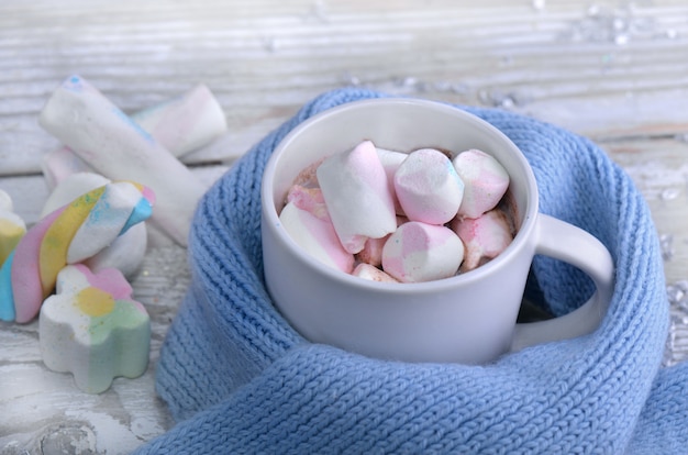 Una tazza piena di marshmallow in cioccolato al latte su una sciarpa bambino blu