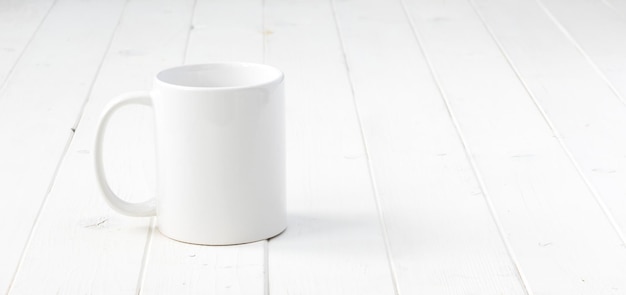 una tazza vuota bianca su un tavolo di legno bianco
