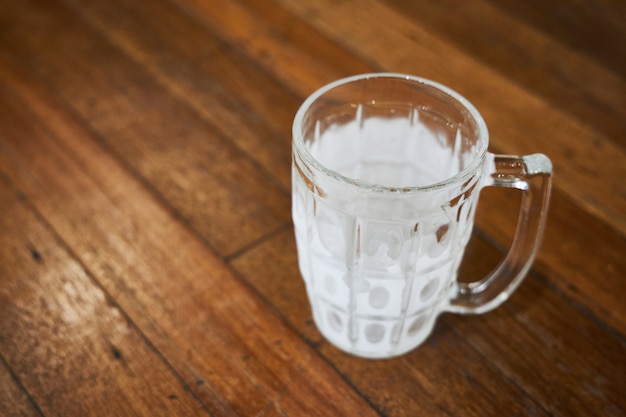 Una tazza vuota di birra coperta di brina si trova su un tavolo di legno di un pub