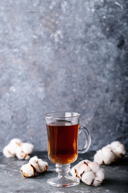 Una teiera di metallo nero e una tazza di tè in tazza di vetro