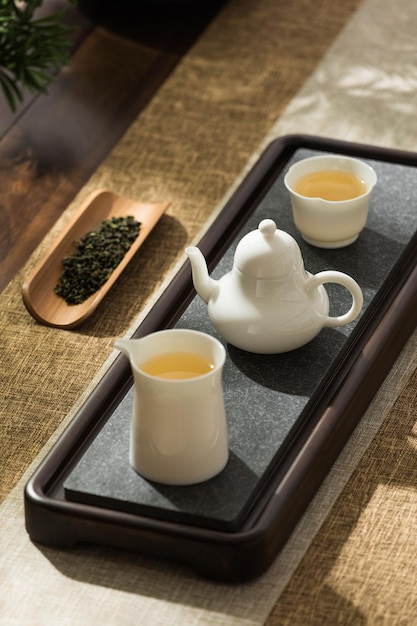 Una teiera e due tazze di tè si trovano su un vassoio con accanto un cucchiaio di legno.