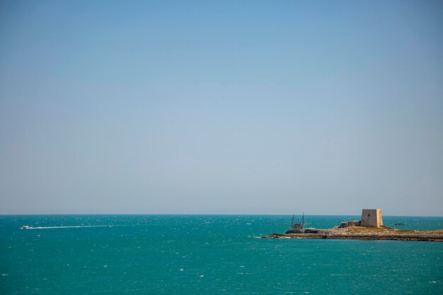 Una torre del castello sulla costa del mare Adriatico con una barca bianca sull'acqua