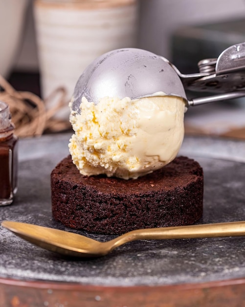 Una torta al cioccolato con gelato alla vaniglia in cima e un cucchiaio a lato.