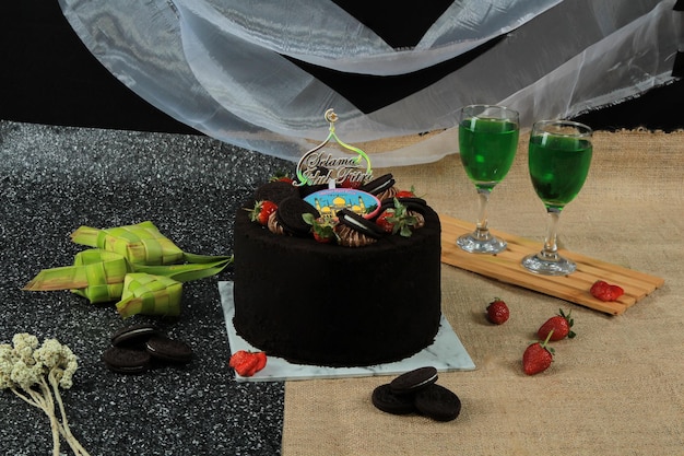 Una torta al cioccolato con una nave pirata in cima si trova su un tavolo accanto a due bicchieri di vino.
